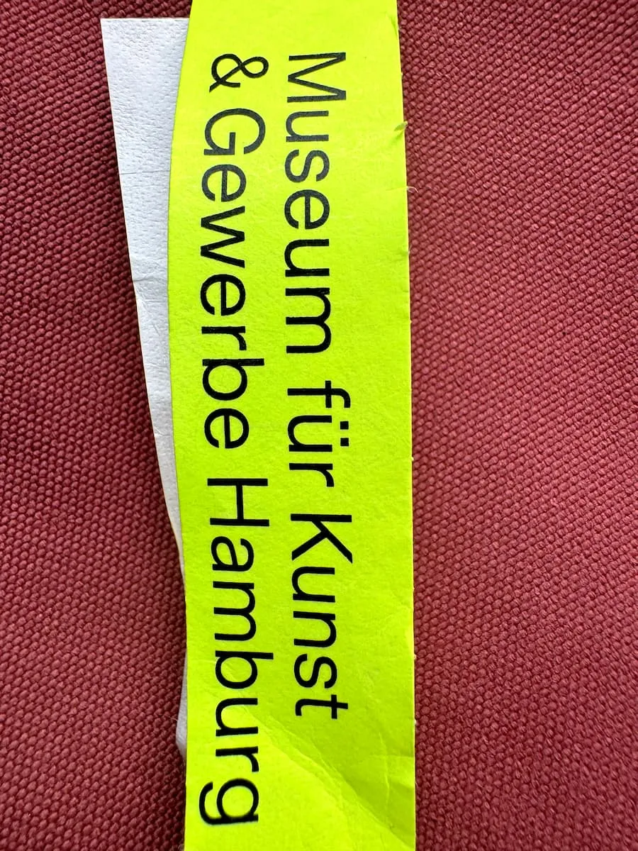 Ein neongelbes Handgelenkbändchen mit der Aufschreift „Museum für Kunst und Gewerbe Hamburg“