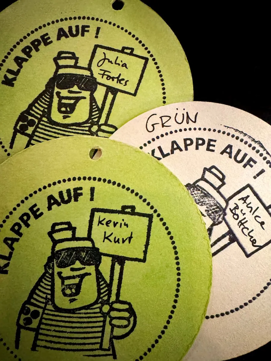 Drei Eintrittskarten für das inklusive Filmfestival „Klappe Auf!“ in Form von Bierdeckeln. Darauf die Namen „Kevin Kurt“, „Julia Fortes“ und „Anke Böttcher“.